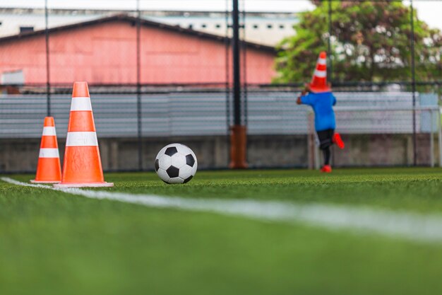 Конус тактики футбольного мяча на траве поля с для обучения фон Обучение детей в футбол