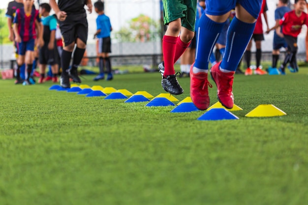 Soccer ball tactics on grass field with barrier cone for\
training children jump skill in soccer academy