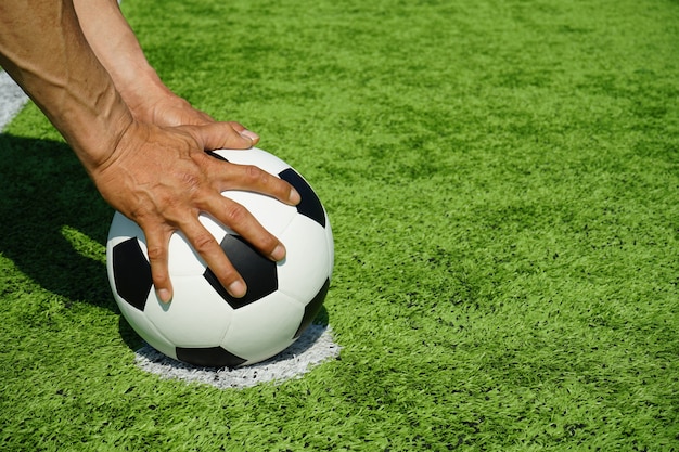 Foto pallone da calcio con le mani e l'erba verde