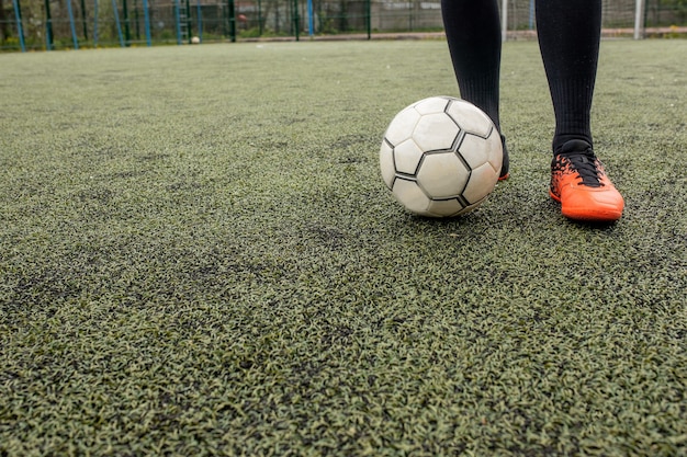 Soccer ball with his feet on the football field.