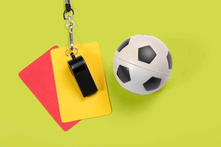 Photo soccer ball, yellow and red cards and referee whistle.