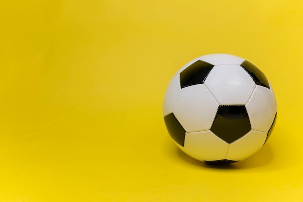 Pallone da calcio sulla superficie gialla dell'armamentario di calcio classico calcio in pelle bianca e nera