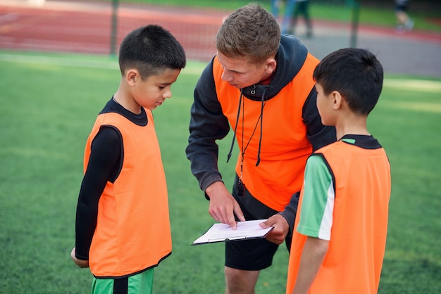 Футбольный тренер показывает своим игрокам стратегию футбольной игры на тренировке.