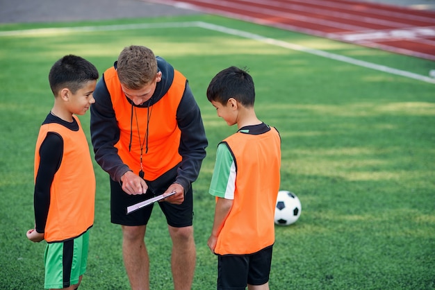 サッカーのコーチは、トレーニングで選手にサッカーの試合の戦略を示します。