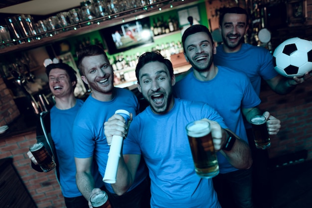 Soccer fans celebrating goal and drinking beer.