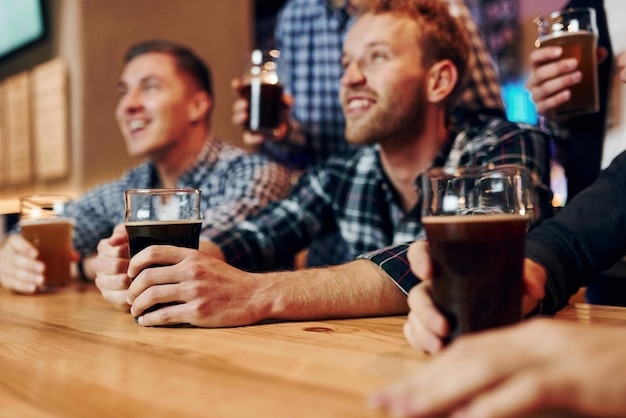 Soccer fans celebrating victory Group of people together indoors in the pub have fun at weekend time