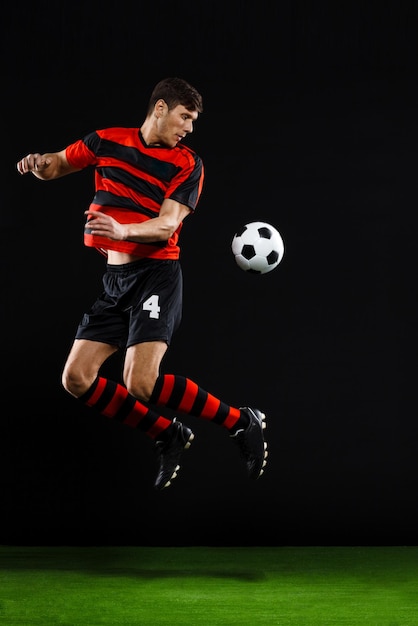 Soccer player kicking ball over black background