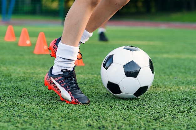 Soccer player kicking ball on field soccer players on training\
session close up footballer feet