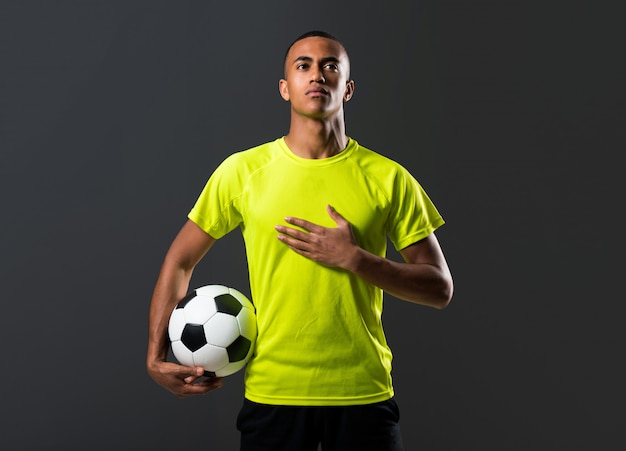 어두운 피부를 가진 축구 선수 남자는 그의 손으로 공을 잡기 및 국가 노래
