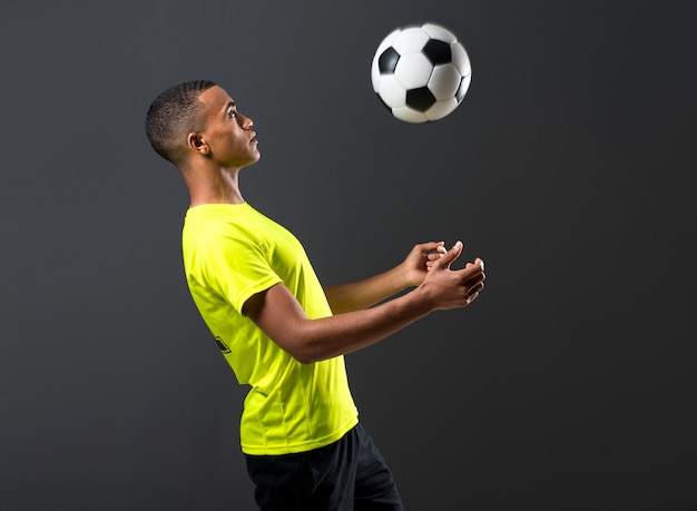 Soccer player man with dark skinned playing on dark background