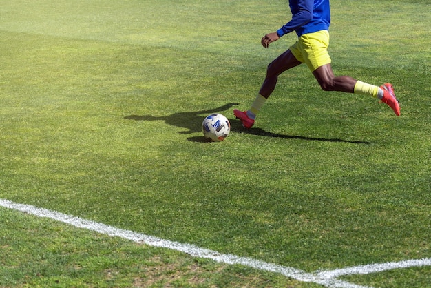Un giocatore di calcio si prepara a calciare la palla su un campo in erba naturale da vicino Foto Premium