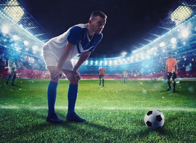 Футболист готов ударить по футбольному мячу на освещенном стадионе во время матча