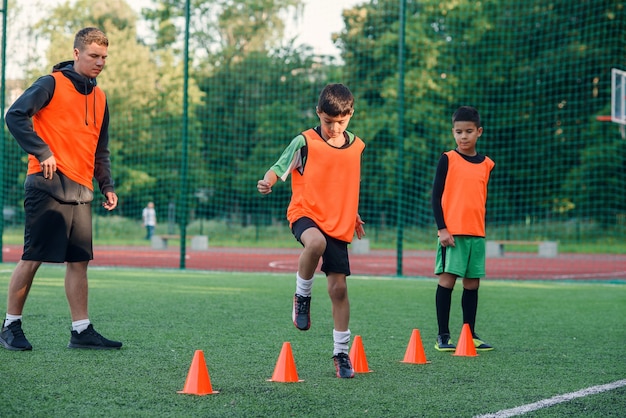 Giocatore di calcio in esecuzione tra i coni arancioni sullo stadio durante l'allenamento