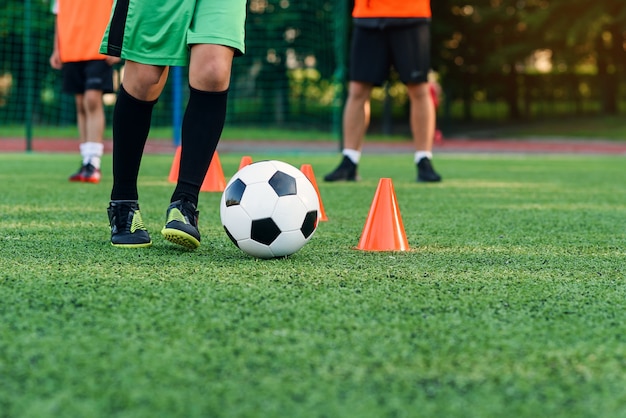 Soccer player running ball among orange cones