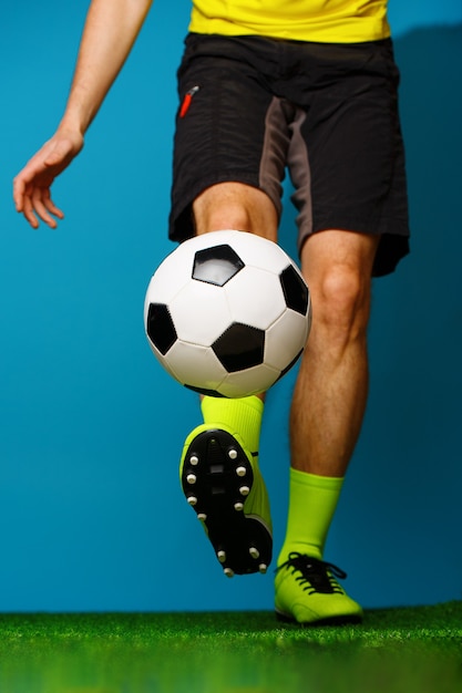 Soccer player with ball on the green grass and blue