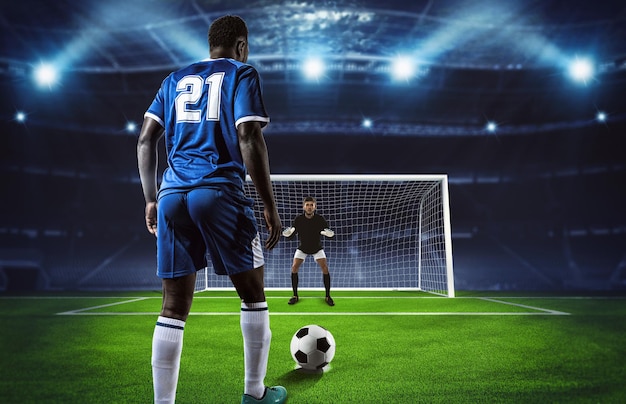 Soccer scene at night match with player in blue uniform kicking the penalty kick