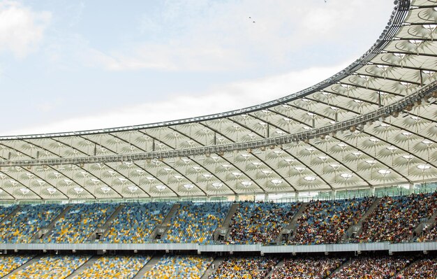 Soccer stadium inside view football field empty stands a crowd of fans a roof against the sky