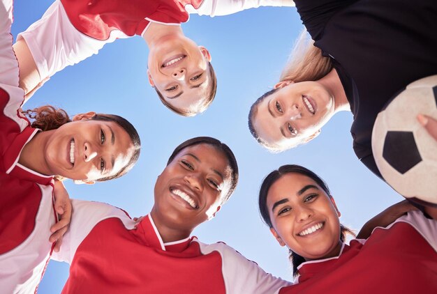 Una squadra di calcio di sole donne in una rannicchiata durante una partita felice di aver vinto la competizione ritratto ad angolo basso di una squadra di calcio femminile in piedi in cerchio in unità e supporto come strategia di gioco