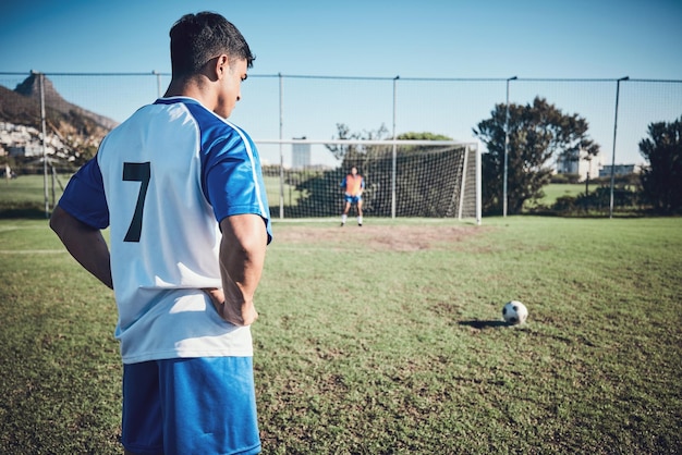 サッカーの思考とゴールを求めるフィールド上の男性スポーツペナルティまたはチームのトレーニングフィットネスの焦点と有酸素運動の勝利またはプレーのための競技中にサッカーを蹴る準備をしているアスリート