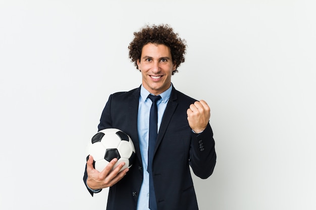 Soccer trainer holding a ball cheering carefree and excited.