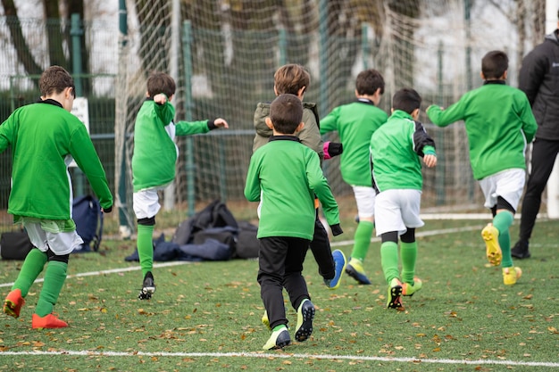 子供のためのサッカートレーニング演習 秋のサッカー芝生フィールドでの男の子のトレーニング コーチとチームの若いスポーティーな子供たち 学童のためのサッカーユニットの練習