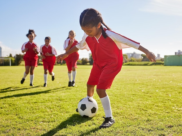 Soccer training or sports and a girl team playing with a ball together on a field for practice Fitness football and grass with kids running or dribblinf on a pitch for competition or exercise