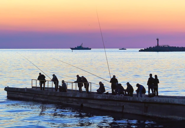 Sochi Russia11012021 Amateur fishermen on the pier near the Black Sea Silhouettes of people