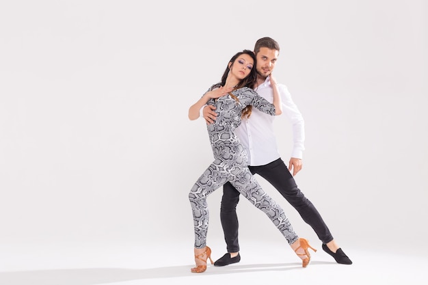 Social dance concept - Active happy adults dancing bachata or salsa together over white surface