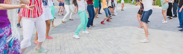 Concetto di ballo sociale e flashmob - divertiti e balla in estate in una strada cittadina. primo piano dei piedi dei ballerini.
