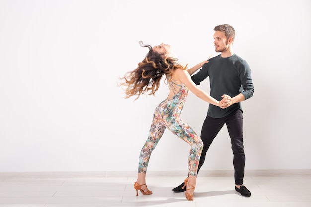 Danza sociale, kizomba, tango, salsa, concetto della gente - bella coppia che balla bachata su fondo bianco con lo spazio della copia