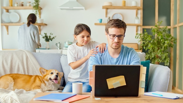 Social Distancing. A Busy Father Tries to Work Remotely with His Child and Wife at Home.