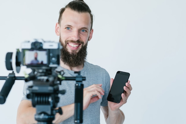 Influencer sui social media al lavoro. blogger che realizza una recensione commerciale o indipendente. uomo che tiene un telefono cellulare davanti a una telecamera. hobby trasformato in un business redditizio.