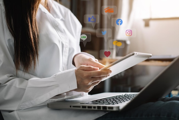 집에서 노트북 컴퓨터와 태블릿으로 키보드를 입력하는 비즈니스 여성의 소셜 미디어 및 마케팅 가상 아이콘 화면
