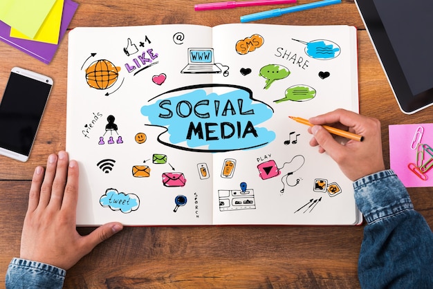 Social media. Top view close-up image of man sketching in his notebook while sitting at the wooden desk