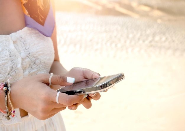 Social network lifestyle business with remote working technology life and travel weather forecasts concepts Cool woman hands using mobile smart phone at beach with sand background on sunny day