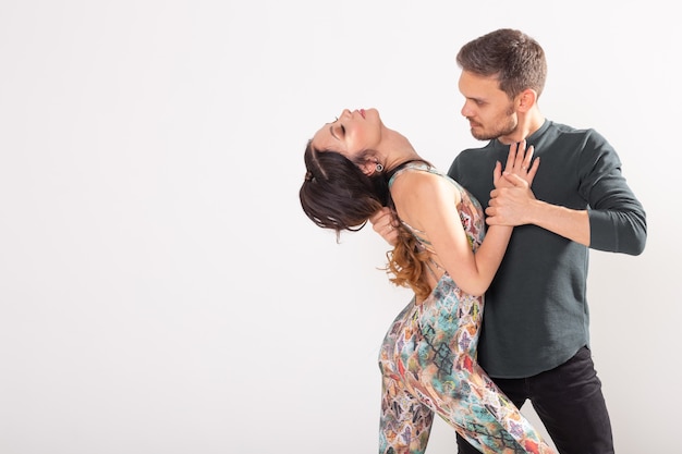 Sociale dans, bachata, salsa, kizomba, zouk, tango concept - Man knuffelt vrouw tijdens het dansen over witte muur met kopie ruimte