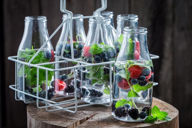 Soda in bottle with berries on dark background