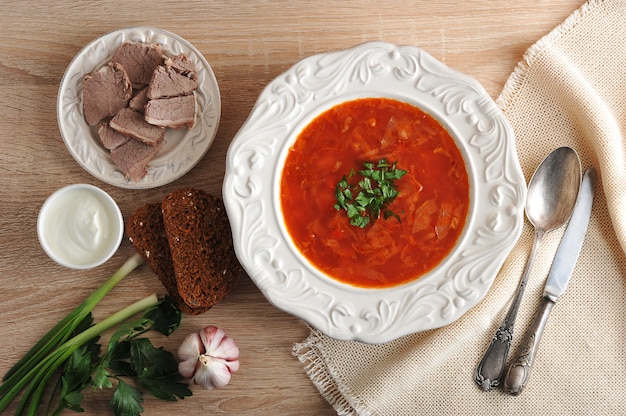 Soep in een kom met dille, zure room en zwart brood op houten oppervlak