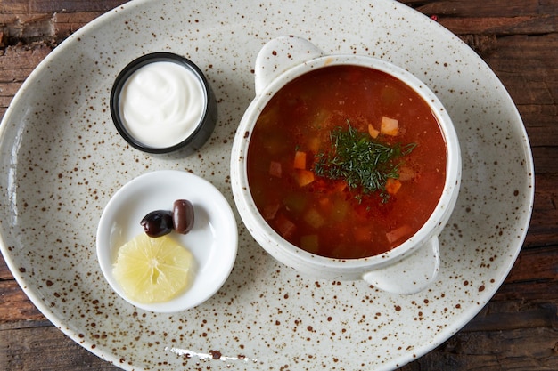 Soep zoutkruid met citroen vlees augurken tomatensaus olijven in een kom op een plundering