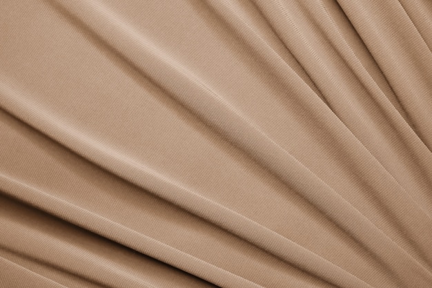 Soepele elegante beige satijnen textuur als abstracte achtergrond. Luxe achtergrondontwerp.