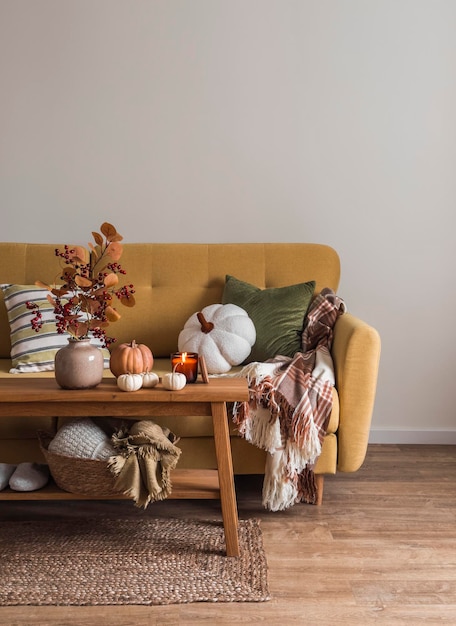 아늑한 가을 거실 내부에는 베개와 담요가 있는 소파, 가을 장식으로 꾸며진 오크 벤치