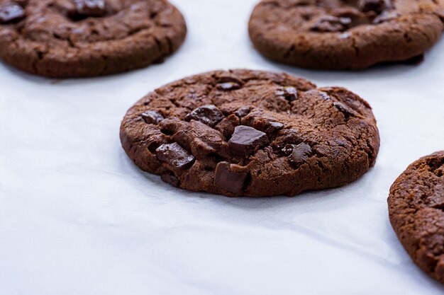 Soft baked chocolate cookies on baking paper, close up picture