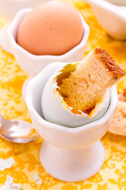 Soft boiled egg in egg cup and served with toast fingers.