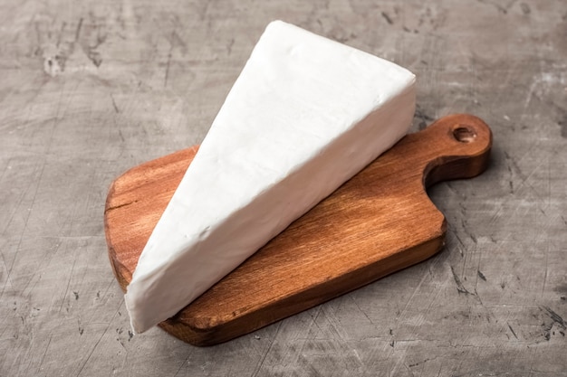 Soft cheese with white mold on a wooden cutting board