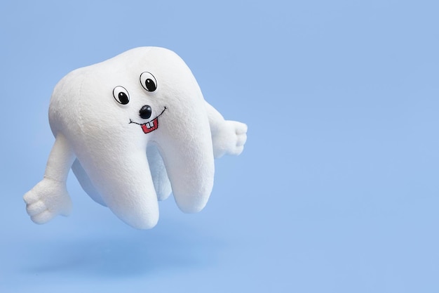 Soft children's toy tooth on a blue background.