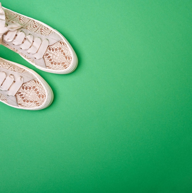 Foto sneaker femminili a maglia cremosa su uno sfondo di carta verde con spazio per la copia