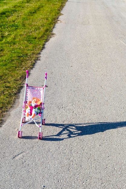 Soft doll in a toy carriage standing in road