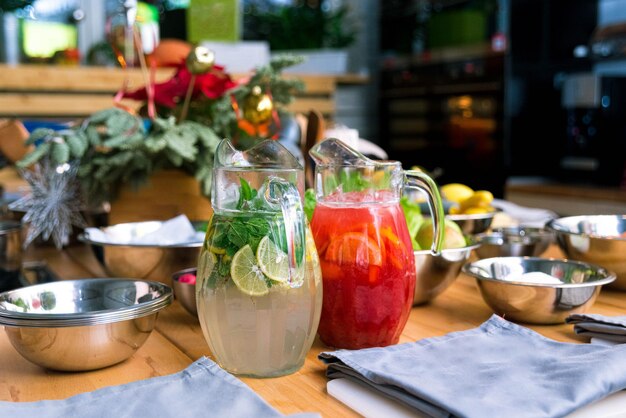 Photo soft drinks lemonades in large glass jugs on the kitchen table