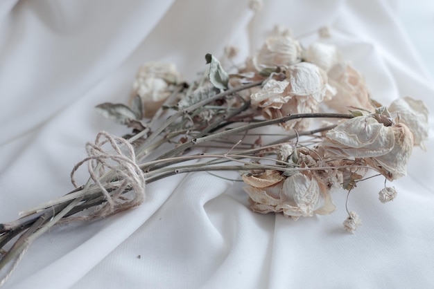 柔らかい生地とドライフラワー、ベッドの上の花、素朴なリボン、ヴィンテージのロープで結ばれた花