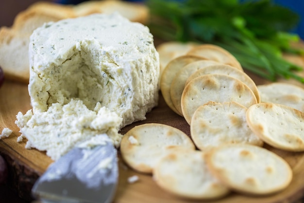 Soft flavored creamy cheese with garlic and fine herbs on a wood board with crackers.